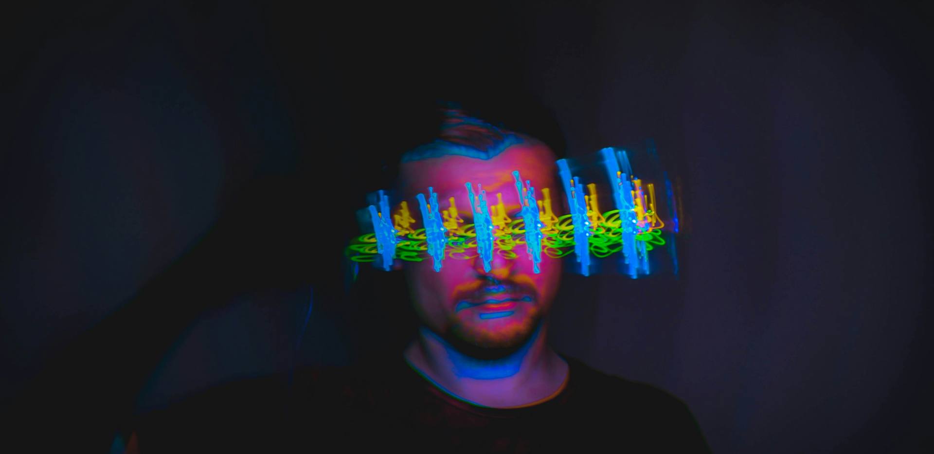 Person die im Dunkeln steht mit Farben um sich herum.