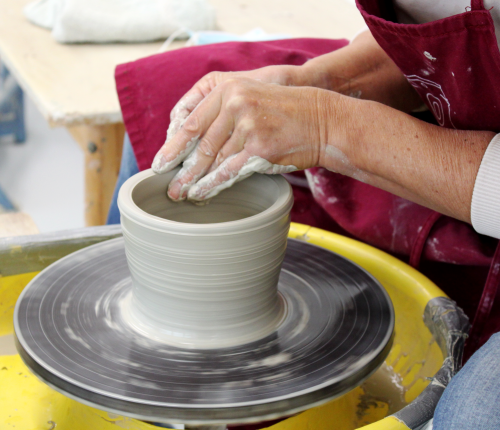 Eine Person arbeitet an einem Gefäß auf der Drehscheibe. Eine Person arbeitet an einem Gefäß auf der Drehscheibe.