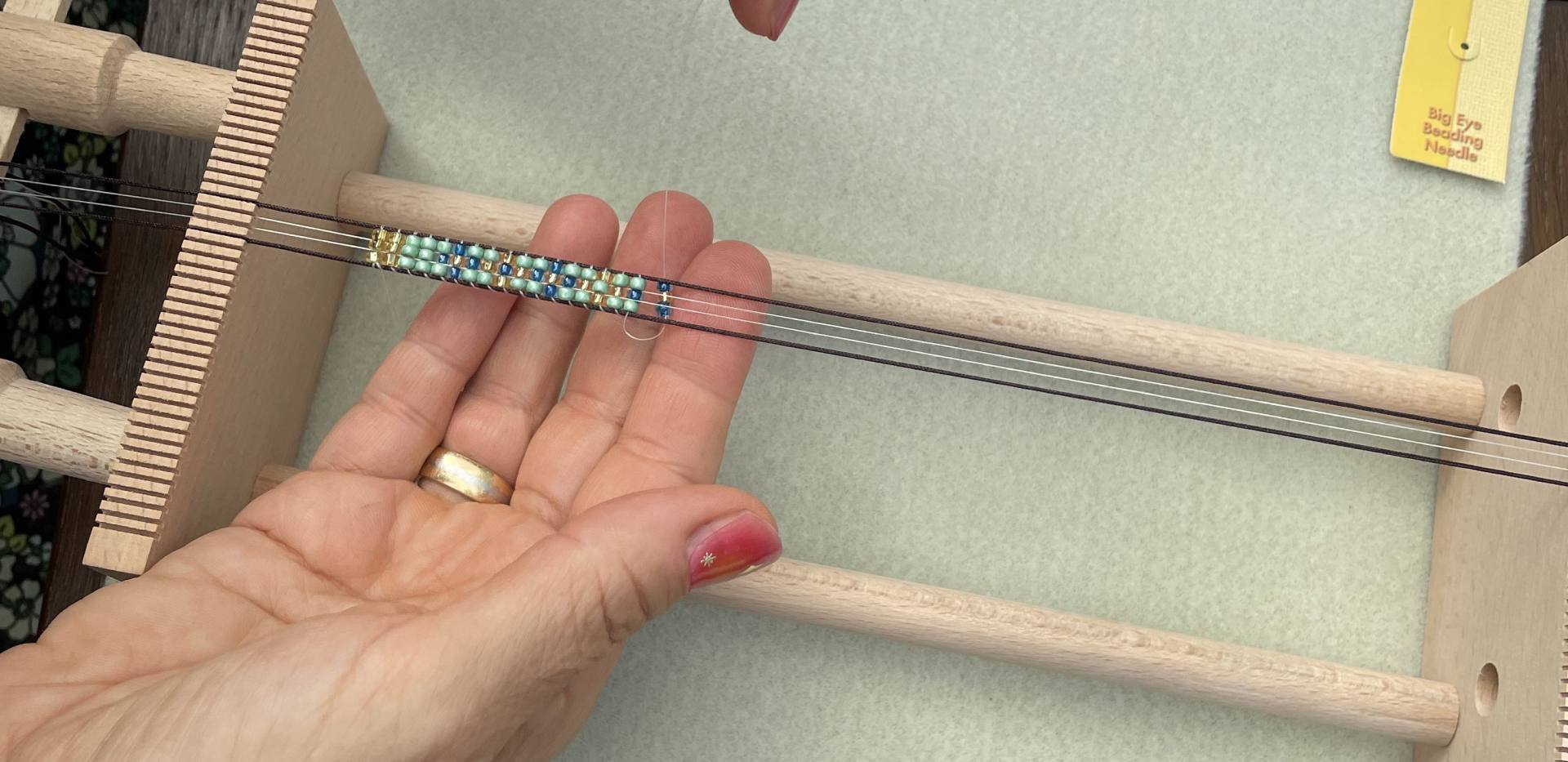Auf dem Bild ist zu sehen, wie jemand Perlen webt.