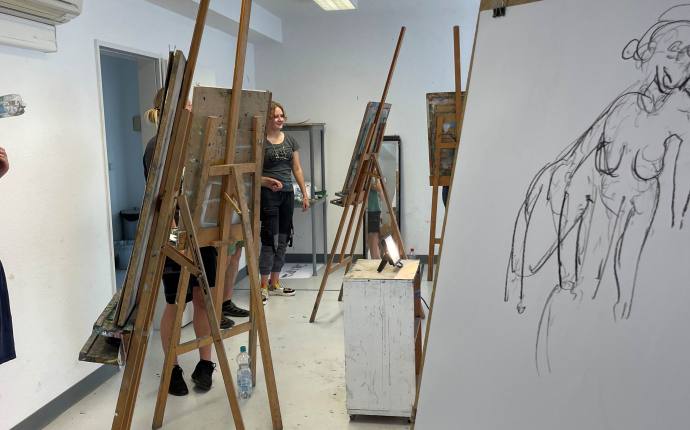Auf dem Foto erkennt man mehrere Staffeleien und Personen. An der vordersten Staffelei wird an einer Aktzeichnung gearbeitet. Auf dem Foto erkennt man mehrere Staffeleien und Personen. An der vordersten Staffelei wird an einer Aktzeichnung gearbeitet.