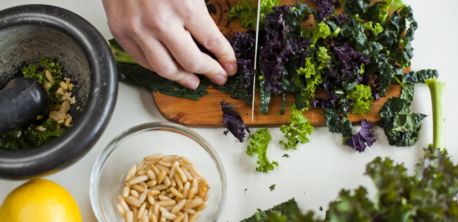 Schneiden einer Gr&uuml;nkohlpflanze mit weiteren Zutaten daneben. 